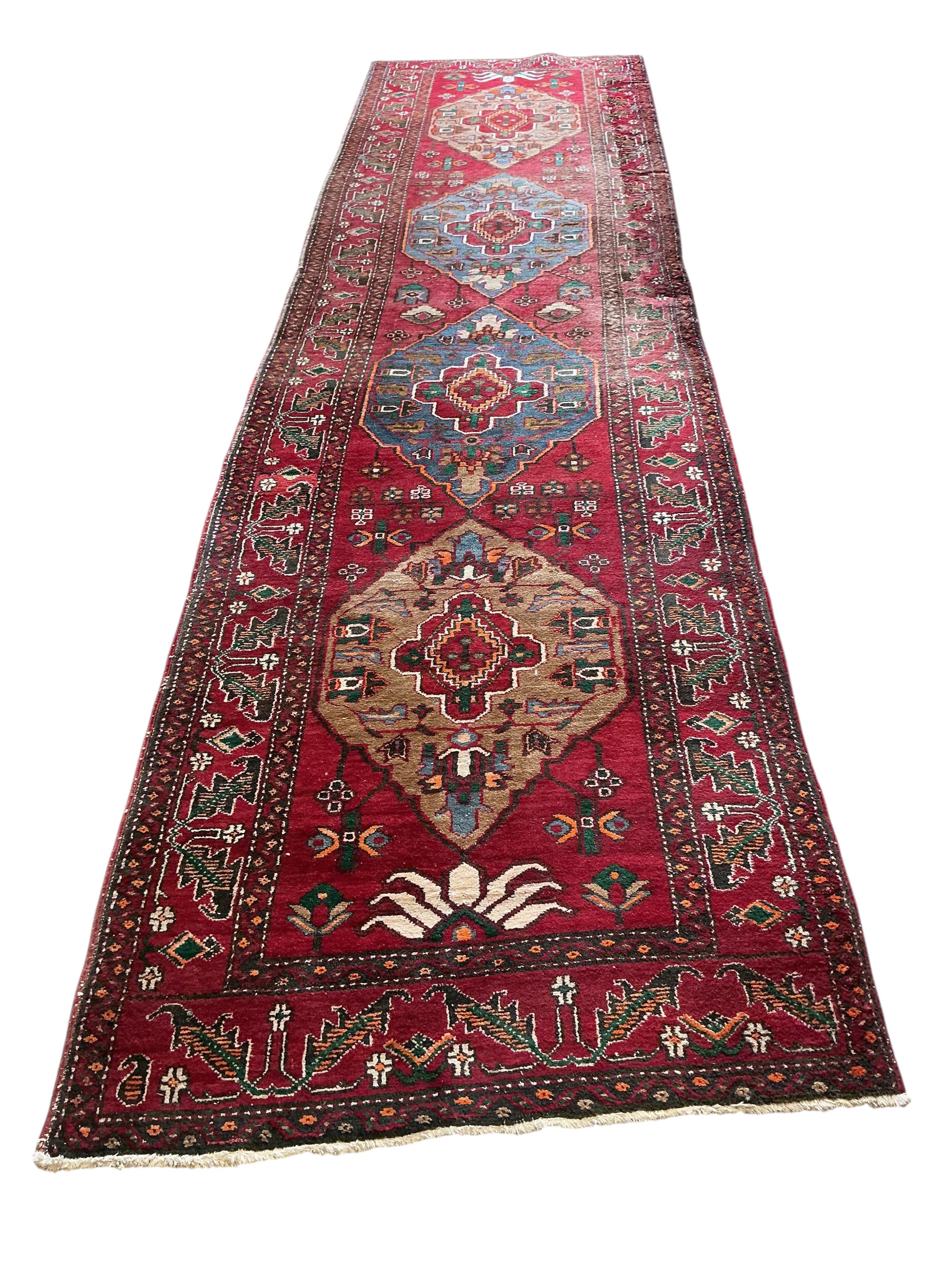 A Caucasian red ground runner, woven with four central elongated octagons, 433 x 113cm